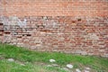 Texture of brick wall with grass at the bottom, background border of old and new brickwork Royalty Free Stock Photo