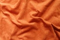 Texture of reddish orange artificial suede fabric in soft folds