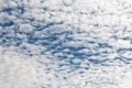 Texture of cloudy blue sky with rows of small fluffy white clouds on warm autumn day