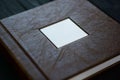 The texture of the cover of a photobook made of genuine brown leather on a black wooden background