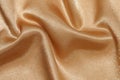 texture crumpled wrinkled gold fabric with glare close-up. elegant background for your design. material for sewing festive