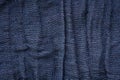 Texture of dark blue wrinkled fabric with vertical folds