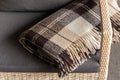 The texture of the fabric of a warm woolen brown beige checkered plaid with fringes.