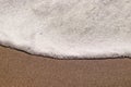 Texture of the foamed wave of the sea on a sandy beach, close up with copy space. Royalty Free Stock Photo