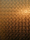 Texture of a frosted glass window through which the rising sun shines has a golden-brown colour