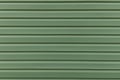 The texture of the green board of the exterior of the house siding panel. Parallel abstract stripes line