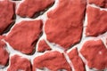 The texture of a homemade plaster fence, painted artificial stone of red brick color. Chaotic spots of different sizes on a