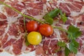 Texture of Italian delicacy dried meat with spices, cherry tomatoes and sprig of parsley. Royalty Free Stock Photo