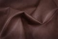 The texture of leather with free space for text. The skin is laid in folds. Genuine leather for furniture. Red leather.