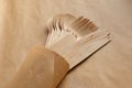 Texture light wooden forks, knives, spoons in a paper bag, on a harmonious craft background.