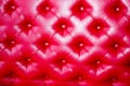 Texture of a luxurious, bright, beautiful, red, stitched leather sofa with rivets, buttons,