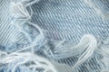 Texture macro with denim of white-blue color with protruding fibers and threads, lacerated, grunge. Details textile
