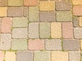 Texture of multicolored beautiful rectangular stone concrete paving brick tiles with seams overgrown with green grass. background Royalty Free Stock Photo