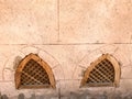 Texture of the old ancient yellow stone strong wall with windows of wooden shutters from below in the Arab Islamic Islamic warm tr