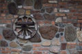 Texture of old brick and stone wall. Old wheel on the wall