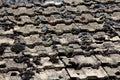 Texture of old dilapidated partially cracked worn out roof tiles covered with small patches of dark green moss