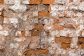 Texture of an old wall of an ancient building with a ruined plaster layer and cracked red bricks, abstract background Royalty Free Stock Photo