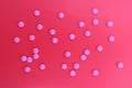 Texture of pink pills on a red background.