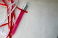 Texture with a pink matte thin long cylindrical perfume bottle, cologne with red and white beautiful festive ribbons made of artif