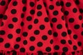 Texture of red fabric with black polka dots - close-up of a fragment of wrinkled cotton fabric