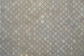 The texture of a rhythmic mosaic made of concrete tiles. Background image of a large area of old and damaged gray tile