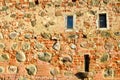 Texture with small narrow windows on an old ancient stone cracked dilapidated brick wall of red brick boulders. The background Royalty Free Stock Photo