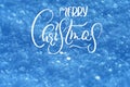 Texture of snow in blue tones background with text Merry Christmas. Calligraphy and lettering