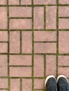 texture of street tiles view from the top with part of the shoes. Brown sidewalk tile pattern Royalty Free Stock Photo