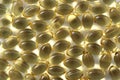 Texture of vitamin capsules of fish oil in golden color.