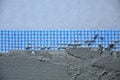 The texture of the wall, covered with gray foam polystyrene plates, covered with a blue reinforcing mesh and covered with a mixtu