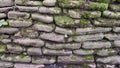 The texture of the wall is made of natural stone flagstone covered with moss. Ancient masonry, vintage background. The wall made