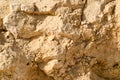 texture of a wall of sandy rock from a yellow friable old rotten stone of rock with shards, holes and layers of sand. The backgro Royalty Free Stock Photo