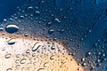 The texture of water droplets on the glass, textured natural gradient of reflections of the blue sky and yellow wall Royalty Free Stock Photo