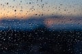 Texture of water drops after rain on glass with sunset outside the window. Blurred sun and sky, beautiful dusk, rainy weather Royalty Free Stock Photo