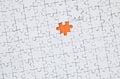 The texture of a white jigsaw puzzle in an assembled state with one missing element forming an orange space Royalty Free Stock Photo