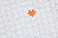 The texture of a white jigsaw puzzle in an assembled state with one missing element forming an orange space Royalty Free Stock Photo