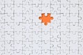 The texture of a white jigsaw puzzle in an assembled state with one missing element forming an orange space Royalty Free Stock Photo