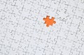 The texture of a white jigsaw puzzle in an assembled state with one missing element forming an orange space Royalty Free Stock Photo