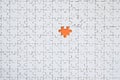 The texture of a white jigsaw puzzle in an assembled state with one missing element forming an orange space Royalty Free Stock Photo