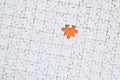 The texture of a white jigsaw puzzle in an assembled state with one missing element forming an orange space Royalty Free Stock Photo