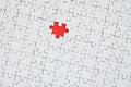 The texture of a white jigsaw puzzle in an assembled state with one missing element forming a red space Royalty Free Stock Photo