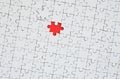 The texture of a white jigsaw puzzle in an assembled state with one missing element forming a red space Royalty Free Stock Photo