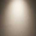 A textured beige wall is illuminated from above by a single light source, highlighting Royalty Free Stock Photo