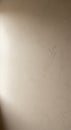 A textured beige wall with subtle shadows and natural light falling from the left. The Royalty Free Stock Photo