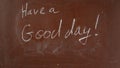 Textured brown chalkboard background. 'Have a good day' is written on the board with a piece of white chalk Royalty Free Stock Photo