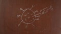 Textured brown chalkboard background. Sketchy virus cell killed by a syringe with vaccine is drawn on the board with a