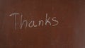 Textured brown chalkboard background. 'Thanks' is written on the board with a piece of white chalk. Close up