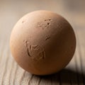 A textured brown sphere on a wooden surface resembling a clay or earthen Royalty Free Stock Photo