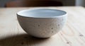 A textured ceramic bowl with a rough, porous surface sits on a light wooden table. The bowl is Royalty Free Stock Photo