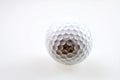 Close-up view of a textured golf ball showcasing its dimples and imperfections against a white background Royalty Free Stock Photo